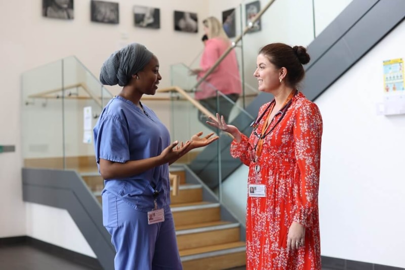 Two doctors speaking together in hospital corridor
